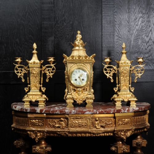 fig 1. A three-piece Louis XVI style gilt bronze clock garniture set comprising a central urn-topped mantel clock flanked by two matching side candelabra.