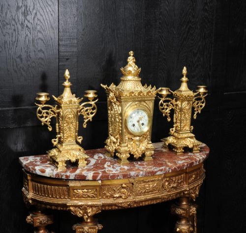 fig 2. A three-piece Louis XVI style gilt bronze clock garniture set comprising a central urn-topped mantel clock flanked by two matching side candelabra.