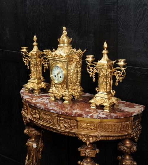 fig 3. A three-piece Louis XVI style gilt bronze clock garniture set comprising a central urn-topped mantel clock flanked by two matching side candelabra.