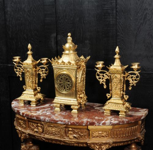 fig 4. A three-piece Louis XVI style gilt bronze clock garniture set comprising a central urn-topped mantel clock flanked by two matching side candelabra.