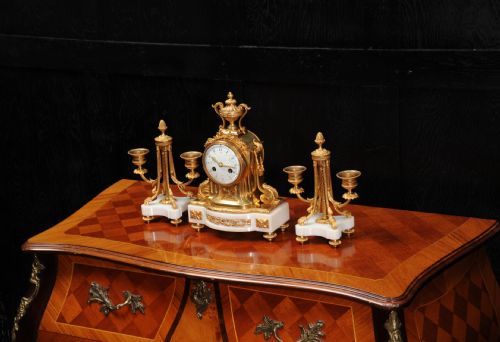 fig 3. A French Louis XVI style clock garniture set featuring a central gilt bronze and white marble mantel clock flanked by two matching two-light candelabra.