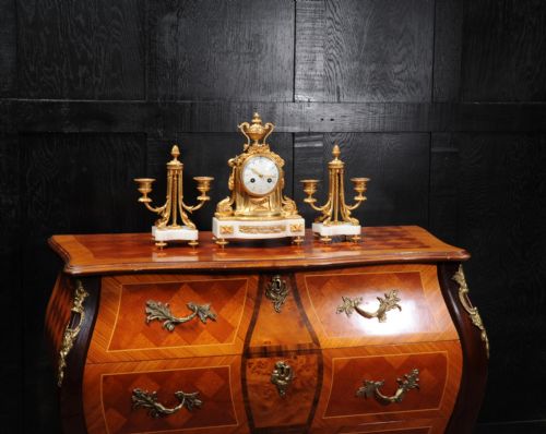 fig 4. A French Louis XVI style clock garniture set featuring a central gilt bronze and white marble mantel clock flanked by two matching two-light candelabra.