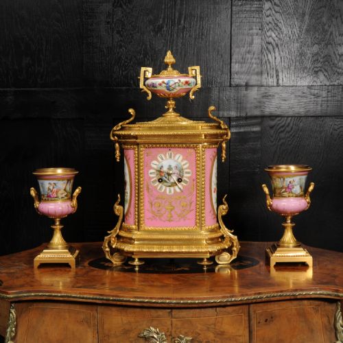fig 1. A French nineteenth-century clock garniture set comprising a gilt bronze and pink painted porcelain mantel clock accompanied by two matching ornamental urns.