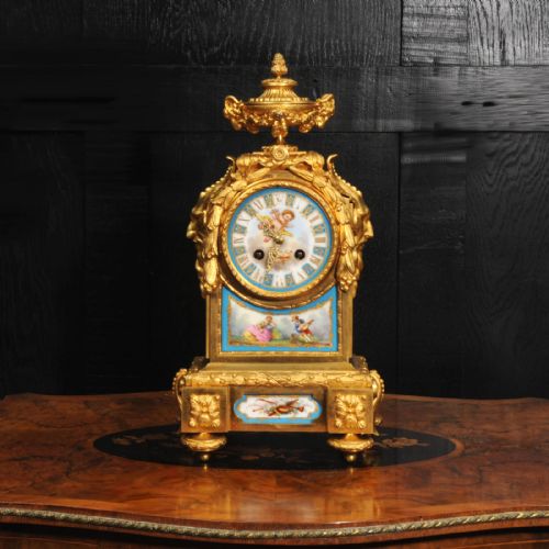 fig 1. A 19th-century French gilt bronze mantel clock set with blue hand-painted porcelain panels depicting figures and an urn finial.