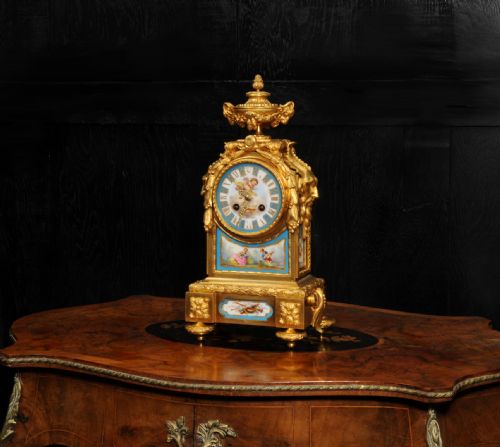 fig 2. A 19th-century French gilt bronze mantel clock set with blue hand-painted porcelain panels depicting figures and an urn finial.