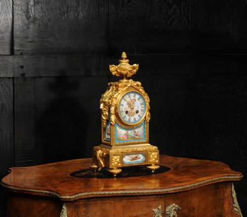 fig 3. A 19th-century French gilt bronze mantel clock set with blue hand-painted porcelain panels depicting figures and an urn finial.