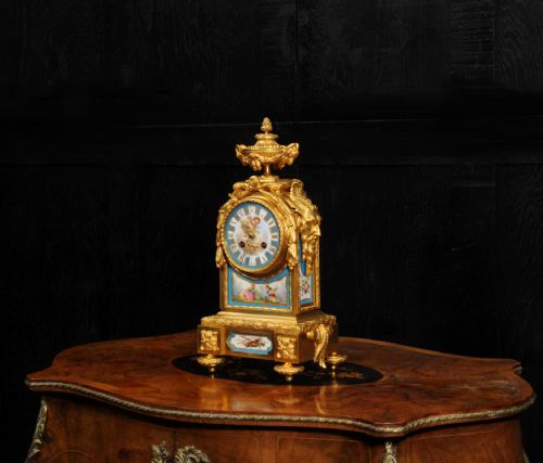 fig 4. A 19th-century French gilt bronze mantel clock set with blue hand-painted porcelain panels depicting figures and an urn finial.