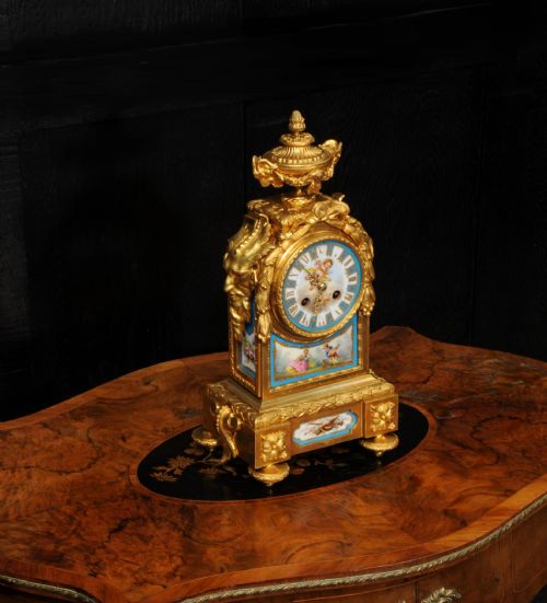 fig 5. A 19th-century French gilt bronze mantel clock set with blue hand-painted porcelain panels depicting figures and an urn finial.