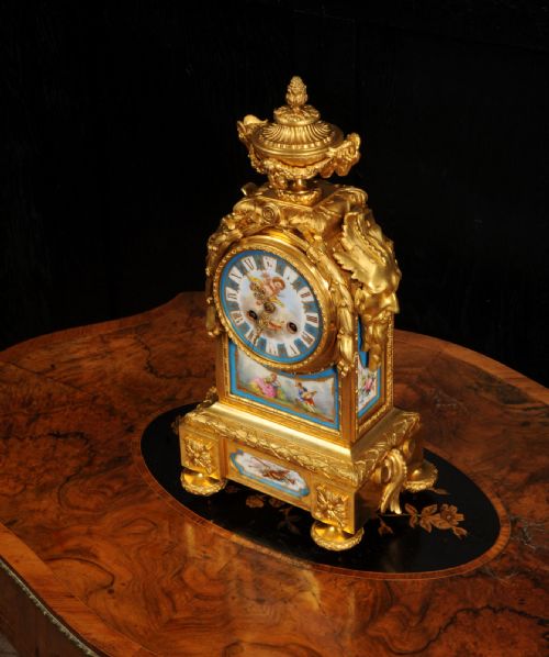 fig 6. A 19th-century French gilt bronze mantel clock set with blue hand-painted porcelain panels depicting figures and an urn finial.