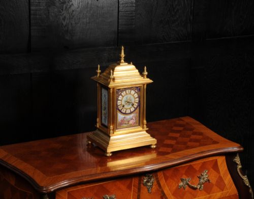 fig 3. An antique gilt bronze mantel clock featuring hand-painted floral and figure porcelain panels, corner columns, and decorative top finials.