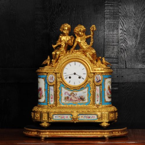 fig 1. A French gilt bronze and celeste blue porcelain mantel clock topped with two gilded cherub figures and hand-painted floral panels surrounding a white enamel dial.