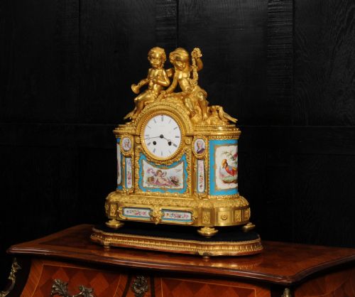 fig 2. A French gilt bronze and celeste blue porcelain mantel clock topped with two gilded cherub figures and hand-painted floral panels surrounding a white enamel dial.