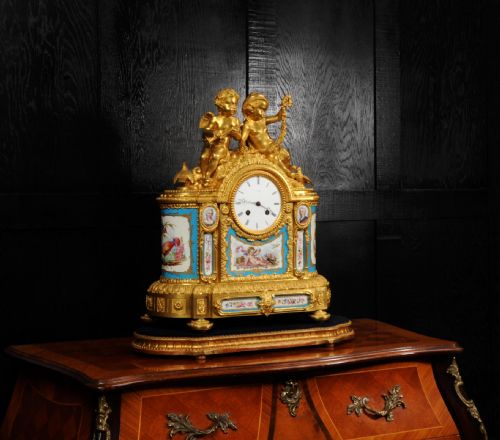 fig 4. A French gilt bronze and celeste blue porcelain mantel clock topped with two gilded cherub figures and hand-painted floral panels surrounding a white enamel dial.