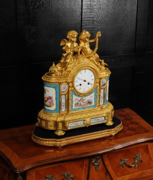 fig 5. A French gilt bronze and celeste blue porcelain mantel clock topped with two gilded cherub figures and hand-painted floral panels surrounding a white enamel dial.