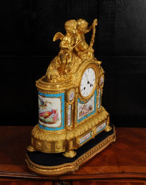 fig 6. A French gilt bronze and celeste blue porcelain mantel clock topped with two gilded cherub figures and hand-painted floral panels surrounding a white enamel dial.