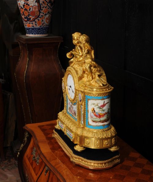 fig 7. A French gilt bronze and celeste blue porcelain mantel clock topped with two gilded cherub figures and hand-painted floral panels surrounding a white enamel dial.