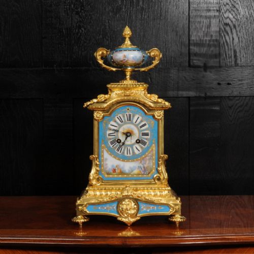 fig 1. An antique French ormolu mantel clock featuring ornate gilt scrollwork, a hand-painted celeste blue porcelain dial, and a matching porcelain urn finial.