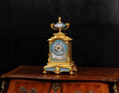 fig 2. An antique French ormolu mantel clock featuring ornate gilt scrollwork, a hand-painted celeste blue porcelain dial, and a matching porcelain urn finial.