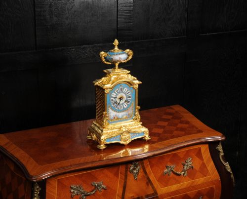 fig 4. An antique French ormolu mantel clock featuring ornate gilt scrollwork, a hand-painted celeste blue porcelain dial, and a matching porcelain urn finial.