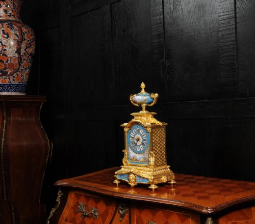 fig 5. An antique French ormolu mantel clock featuring ornate gilt scrollwork, a hand-painted celeste blue porcelain dial, and a matching porcelain urn finial.