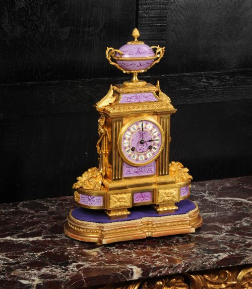 fig 1. An ornate French gilt bronze and lilac hand-painted porcelain mantel clock featuring a decorative urn finial and fluted side columns.