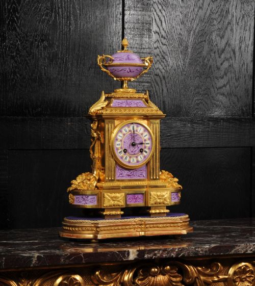 fig 4. An ornate French gilt bronze and lilac hand-painted porcelain mantel clock featuring a decorative urn finial and fluted side columns.