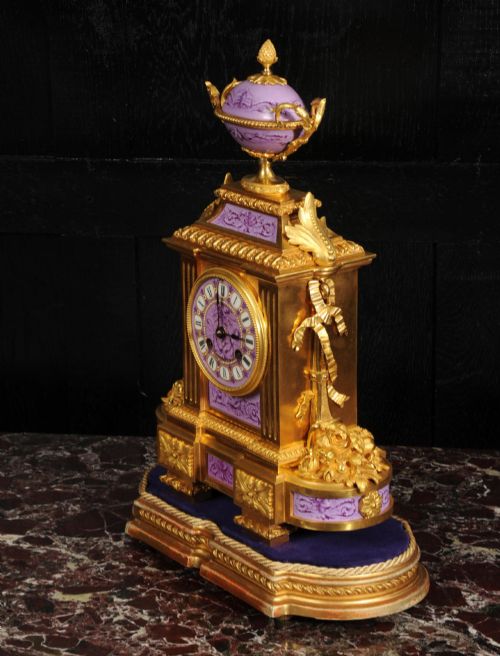 fig 6. An ornate French gilt bronze and lilac hand-painted porcelain mantel clock featuring a decorative urn finial and fluted side columns.