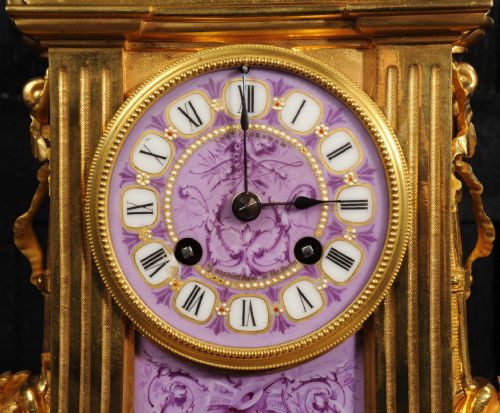 fig 7. An ornate French gilt bronze and lilac hand-painted porcelain mantel clock featuring a decorative urn finial and fluted side columns.
