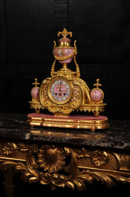 fig 4. An ornate 19th-century French gilt-bronze and pink Sevres porcelain mantel clock featuring scrolled ormolu mounts and hand-painted cherubs.