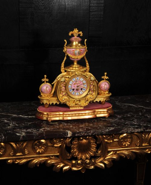 fig 6. An ornate 19th-century French gilt-bronze and pink Sevres porcelain mantel clock featuring scrolled ormolu mounts and hand-painted cherubs.