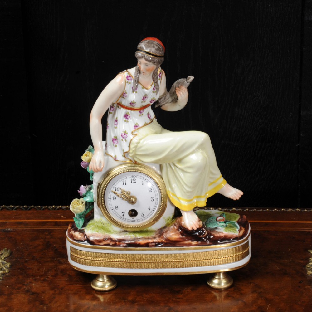 A late 19th-century Vienna porcelain clock featuring a hand-painted seated female figure atop a gilded metal base.