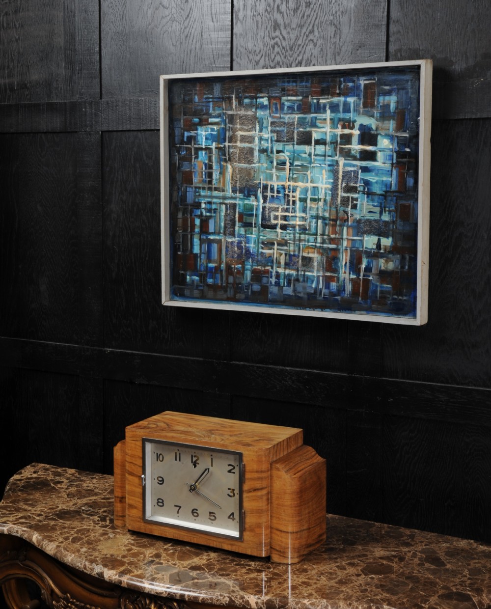 An Art Deco mantel clock featuring a figurative walnut veneered wooden case with stepped sides and a rectangular silver-toned dial with bold black numerals. View V