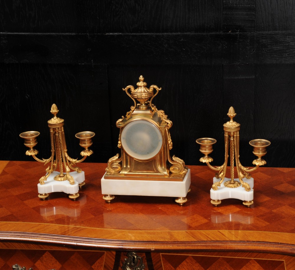 A French Louis XVI style clock garniture set featuring a central gilt bronze and white marble mantel clock flanked by two matching two-light candelabra. View XI