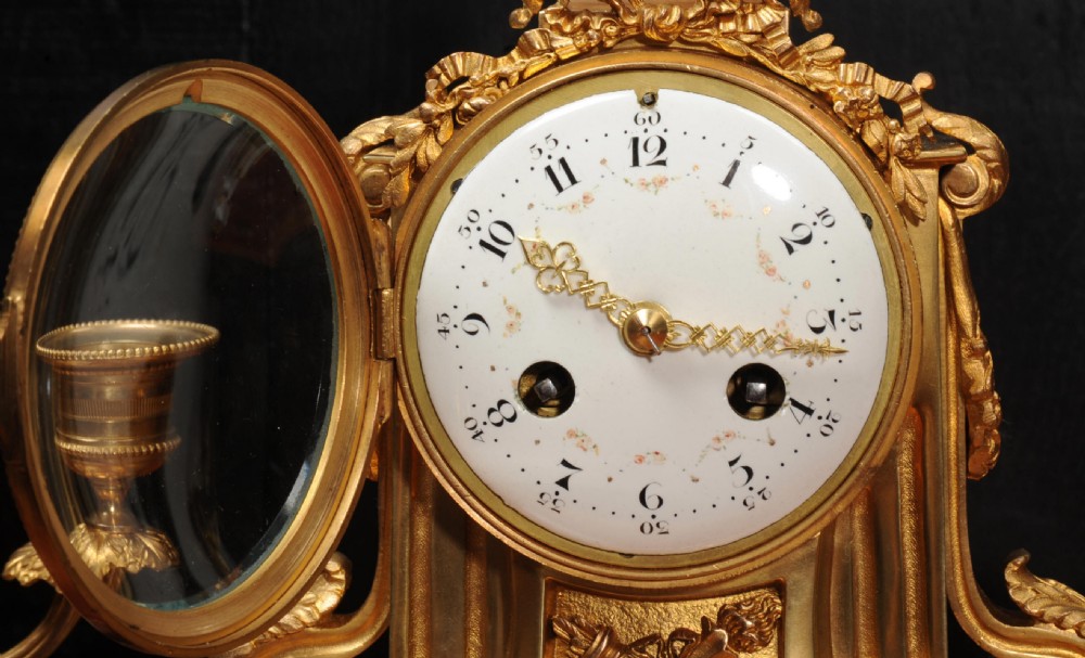 A French Louis XVI style clock garniture set featuring a central gilt bronze and white marble mantel clock flanked by two matching two-light candelabra. View XII