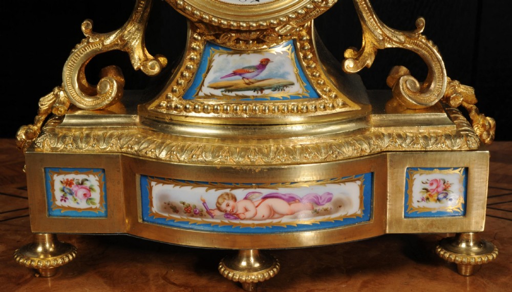 A French 19th-century gilt bronze and Sevres porcelain mantel clock featuring hand-painted floral and cherub panels, an enamelled dial, and a torch and wreath finial. View XI