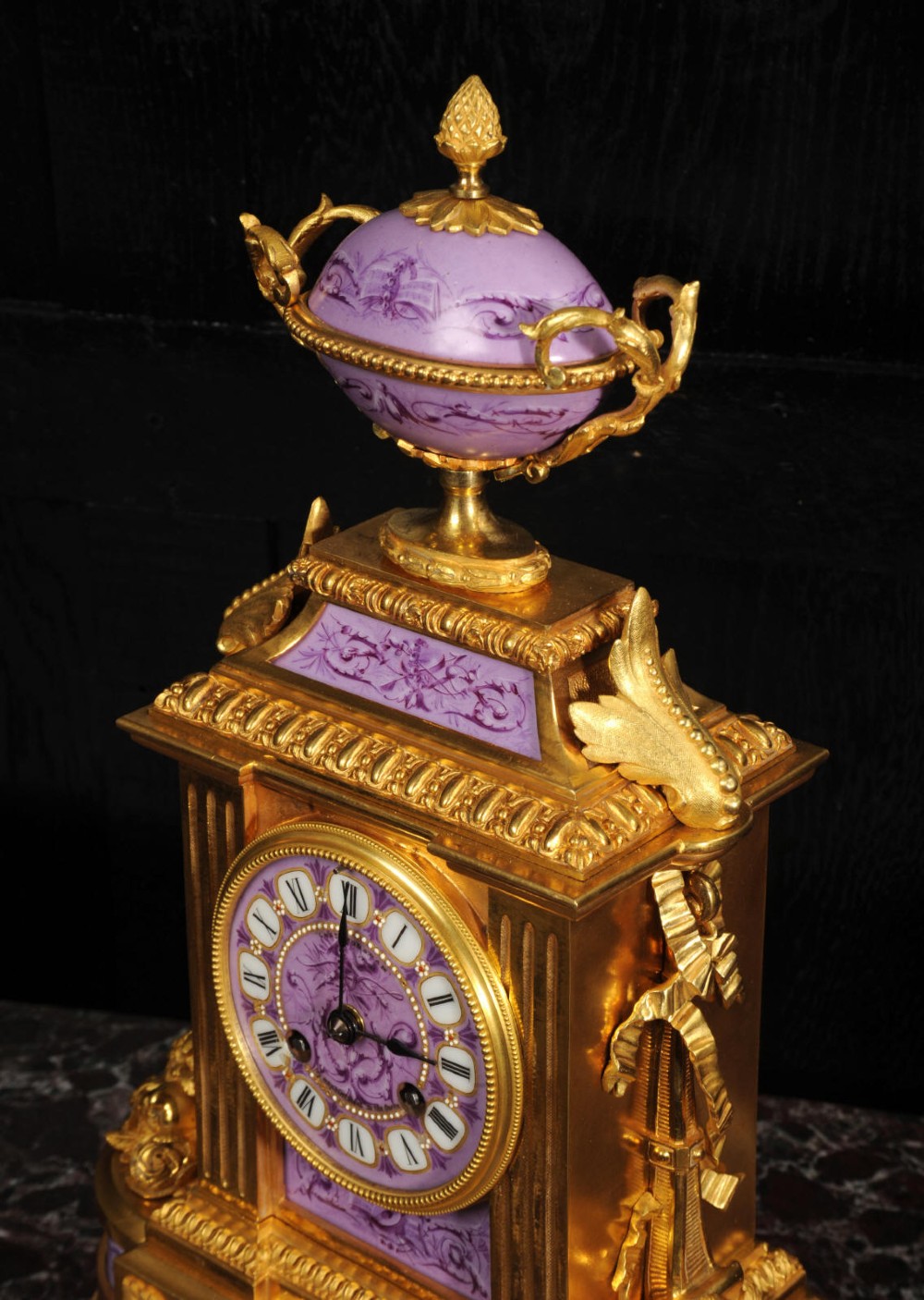 An ornate French gilt bronze and lilac hand-painted porcelain mantel clock featuring a decorative urn finial and fluted side columns. View IV