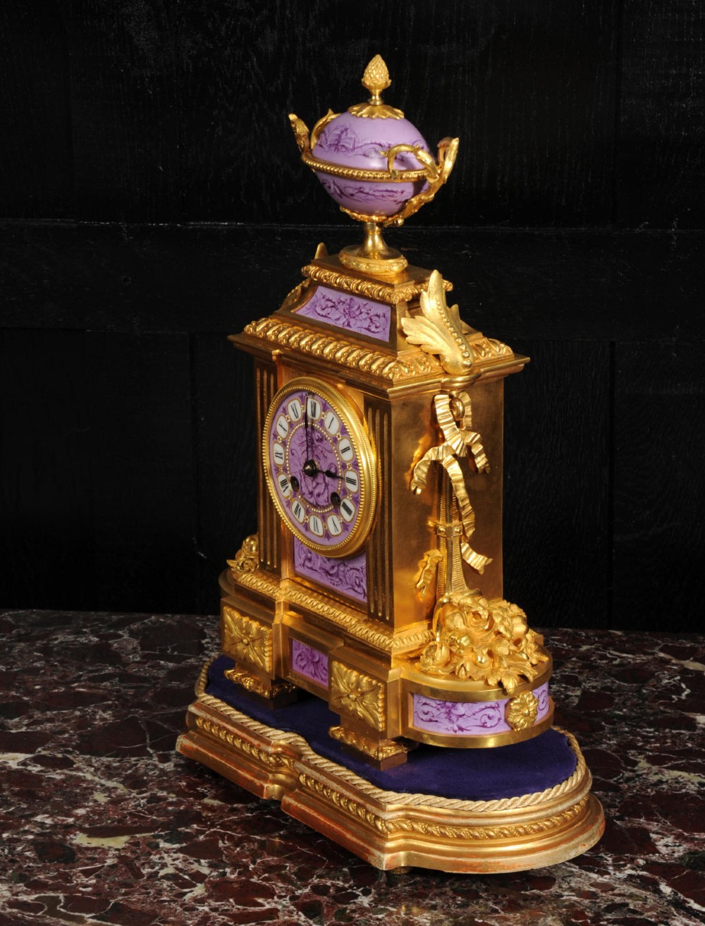 An ornate French gilt bronze and lilac hand-painted porcelain mantel clock featuring a decorative urn finial and fluted side columns. View VII