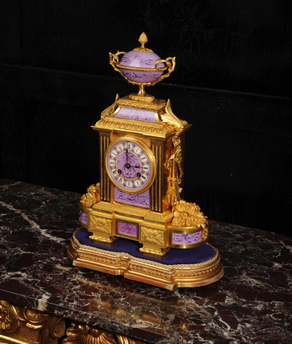 An ornate French gilt bronze and lilac hand-painted porcelain mantel clock featuring a decorative urn finial and fluted side columns. View XII