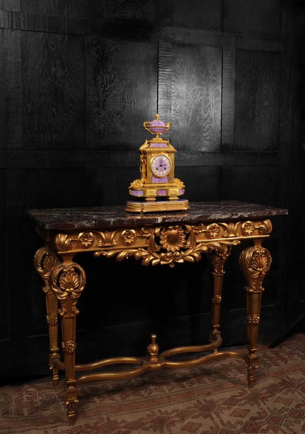 An ornate French gilt bronze and lilac hand-painted porcelain mantel clock featuring a decorative urn finial and fluted side columns. View XIV