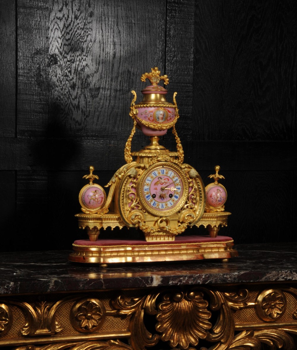 An ornate 19th-century French gilt-bronze and pink Sevres porcelain mantel clock featuring scrolled ormolu mounts and hand-painted cherubs. View II