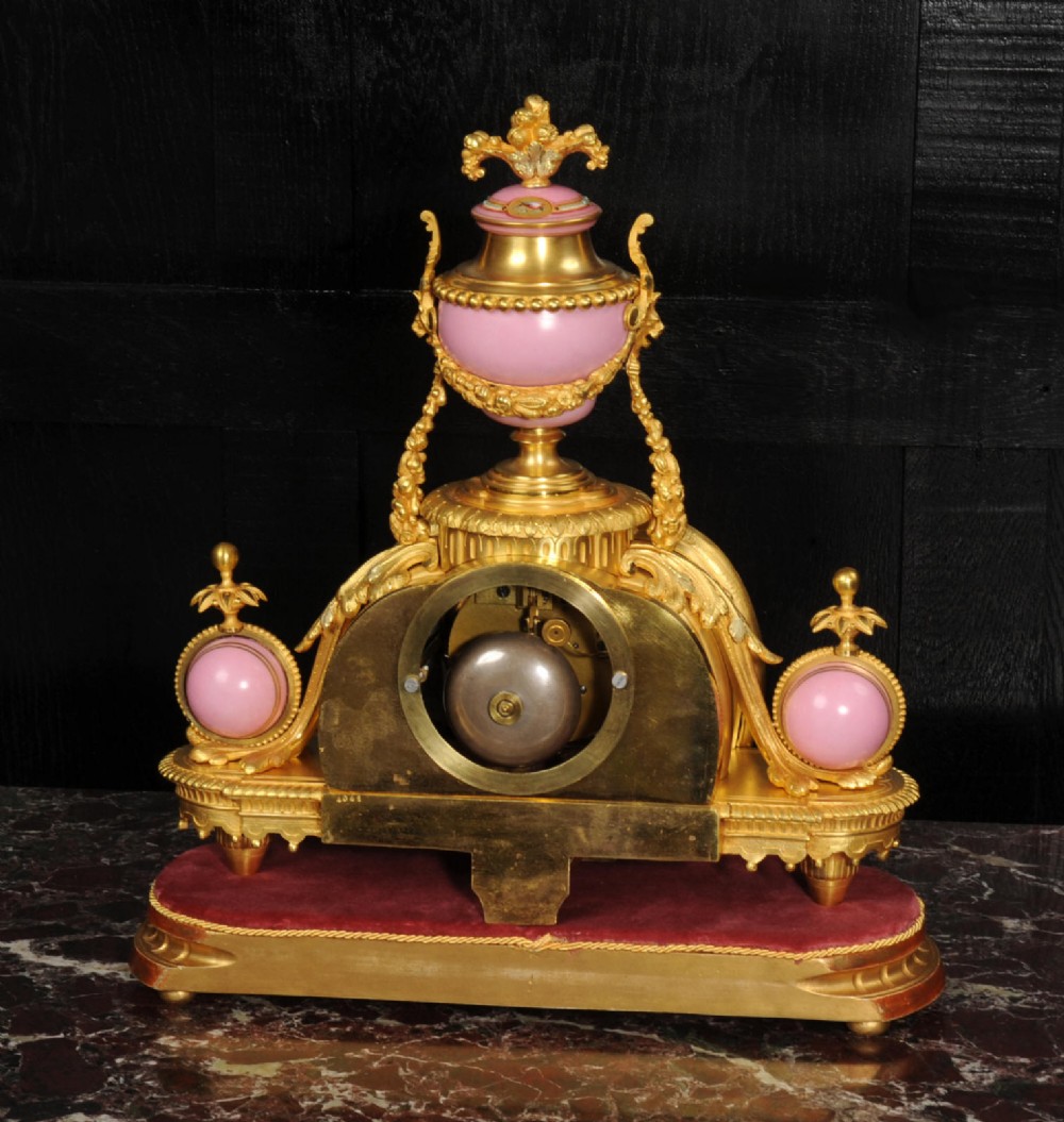 An ornate 19th-century French gilt-bronze and pink Sevres porcelain mantel clock featuring scrolled ormolu mounts and hand-painted cherubs. View VIII