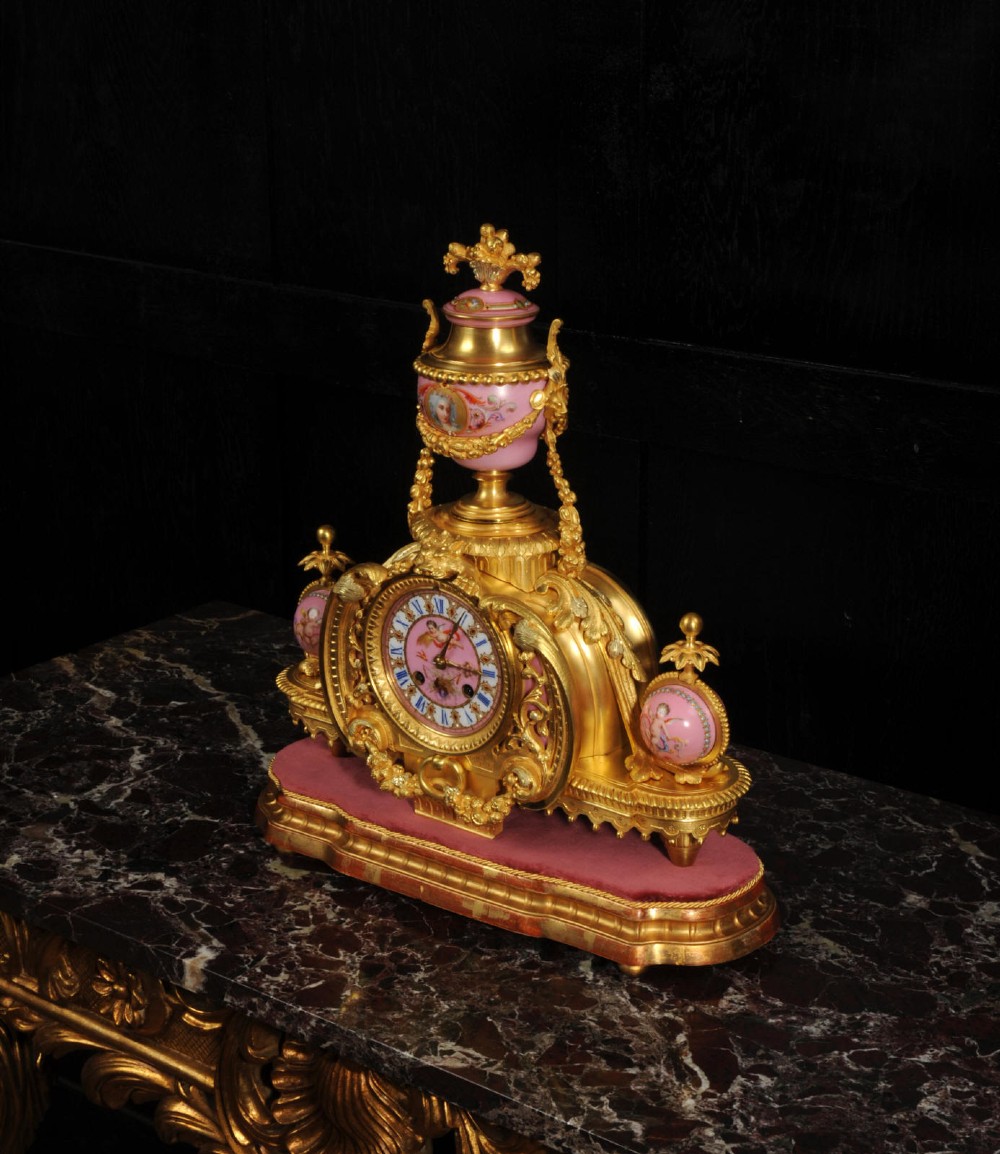 An ornate 19th-century French gilt-bronze and pink Sevres porcelain mantel clock featuring scrolled ormolu mounts and hand-painted cherubs. View IX