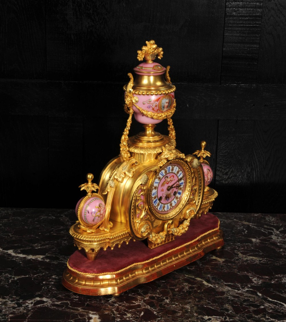 An ornate 19th-century French gilt-bronze and pink Sevres porcelain mantel clock featuring scrolled ormolu mounts and hand-painted cherubs. View XI