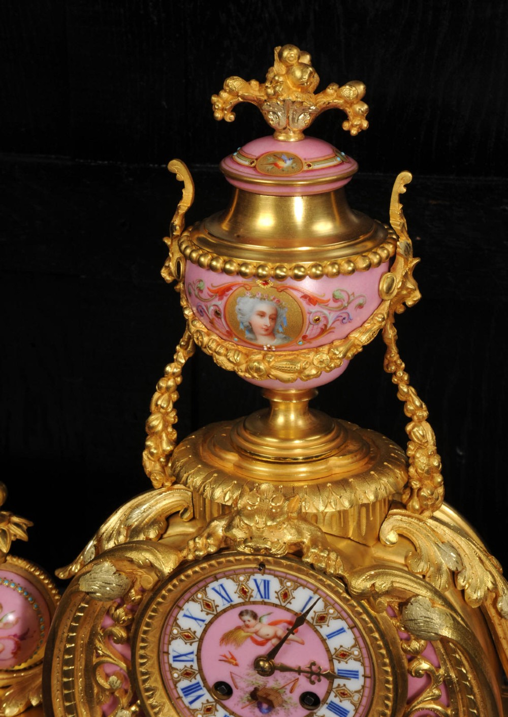 An ornate 19th-century French gilt-bronze and pink Sevres porcelain mantel clock featuring scrolled ormolu mounts and hand-painted cherubs. View XIII