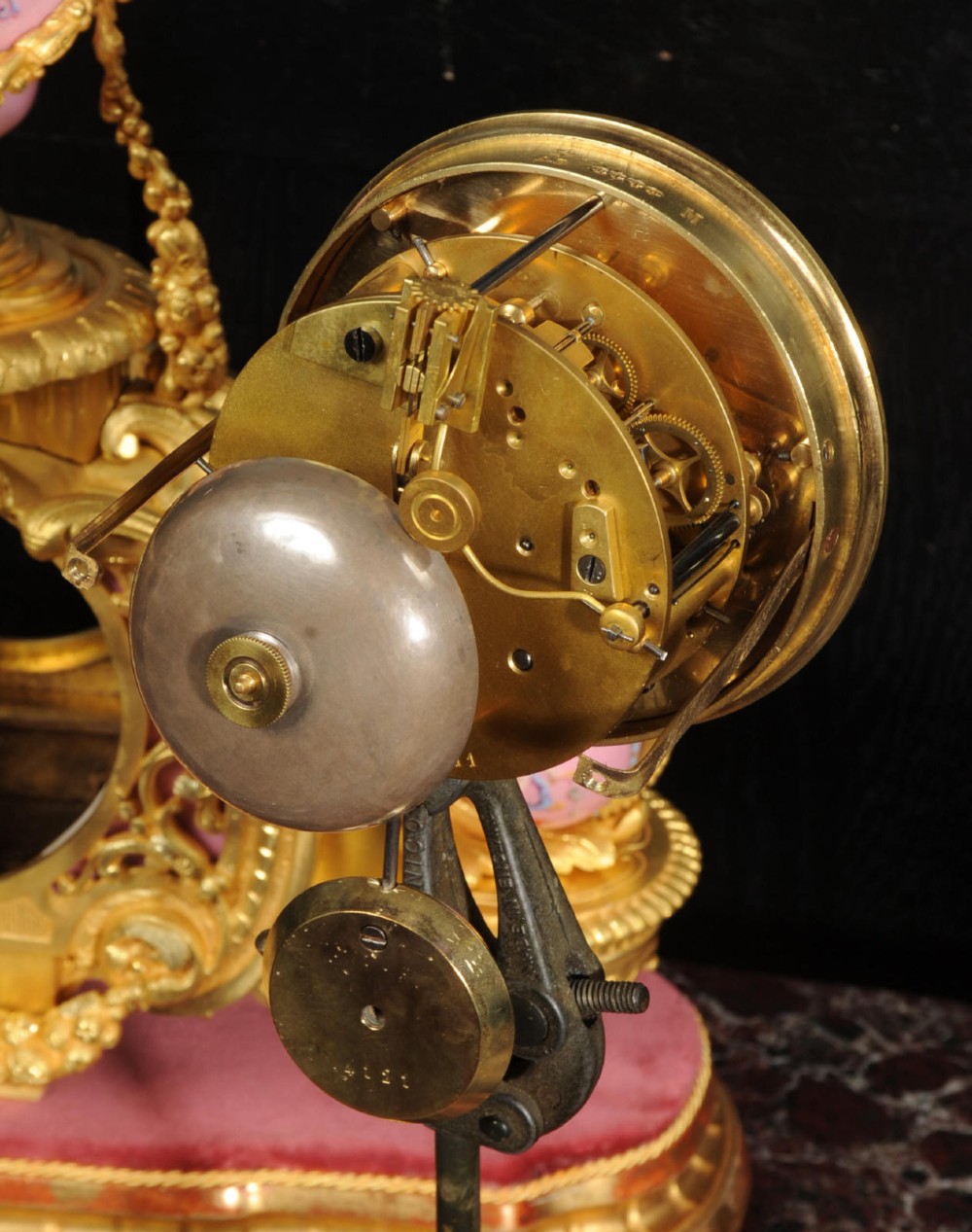An ornate 19th-century French gilt-bronze and pink Sevres porcelain mantel clock featuring scrolled ormolu mounts and hand-painted cherubs. View XIV