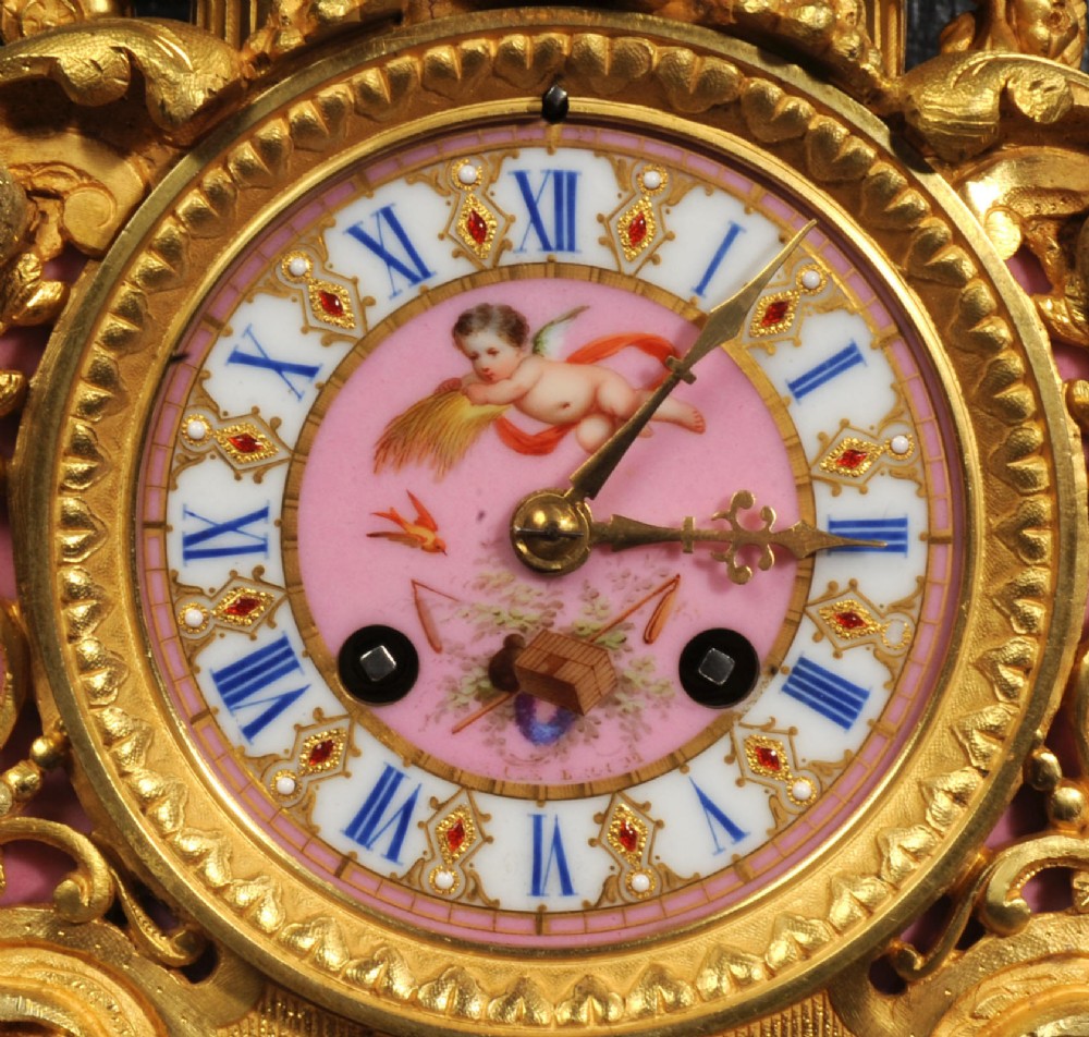 An ornate 19th-century French gilt-bronze and pink Sevres porcelain mantel clock featuring scrolled ormolu mounts and hand-painted cherubs. View XV