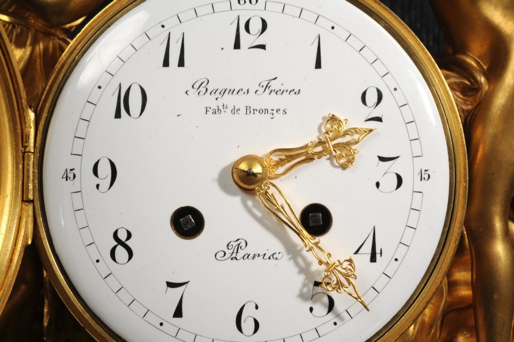 An antique French ormolu and white marble mantel clock featuring gilt bronze figures of Cupid and Psyche surrounding a central white enamel dial on a rectangular marble base. View XIII