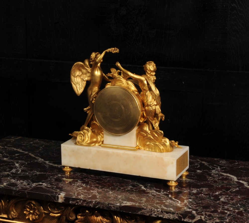 An antique French ormolu and white marble mantel clock featuring gilt bronze figures of Cupid and Psyche surrounding a central white enamel dial on a rectangular marble base. View XIV