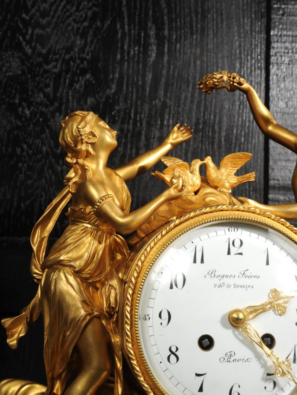 An antique French ormolu and white marble mantel clock featuring gilt bronze figures of Cupid and Psyche surrounding a central white enamel dial on a rectangular marble base. View XV