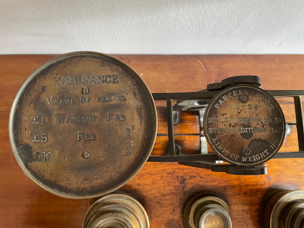 A set of Victorian brass postal scales mounted on a rectangular wooden base with nested brass weights stored in custom cutouts. View II